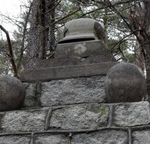 pomnik zwieńczony hełmem żołnierskim i kamiennymi kulami
